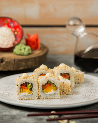sushi rolls with red and yellow bell pepper, cucumber topped with sesame