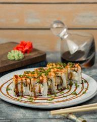 sushi rolls with shrimp and cucumber covered with salmon, soy sauce and onions