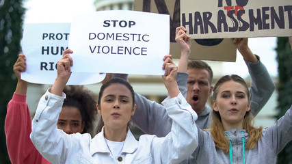 Crowd chanting slogans on domestic violence rally waving banners for human right