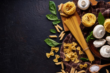 ingredients for cooking traditional pasta with mushrooms on dark stone background Top view Copyspace