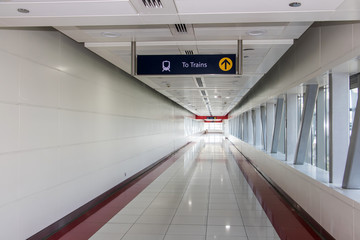 The empty corridor with signboard shows way to the train station. 