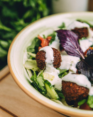 close up half of meatball salad garnished with yoghurt sauce