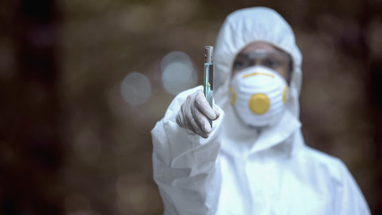 Chemist showing laboratory test tube with blue liquid marked caution, danger