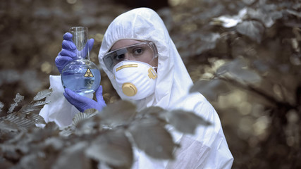 Lab worker holding biohazard test tube, dangerous virus, global threat pollution