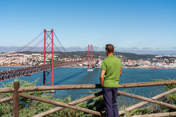 A male tourist contemplates a view of the bridge on April 25 in Lisbon.