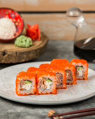 plate of sushi rolls with salmon, cucumber covered in red tobiko