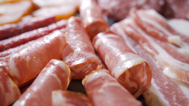 Assorted deli meats, ham, salami, bacon and tomatoes on the black stone tray