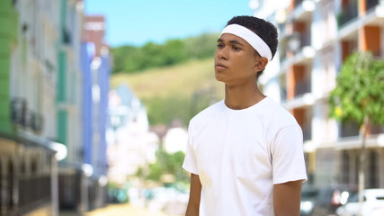 Fototapeta premium Exhausted mixed-race teen sportsman standing on street after hard training