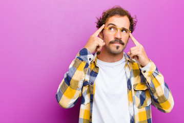 young handsome man looking concentrated and thinking hard on an idea, imagining a solution to a...