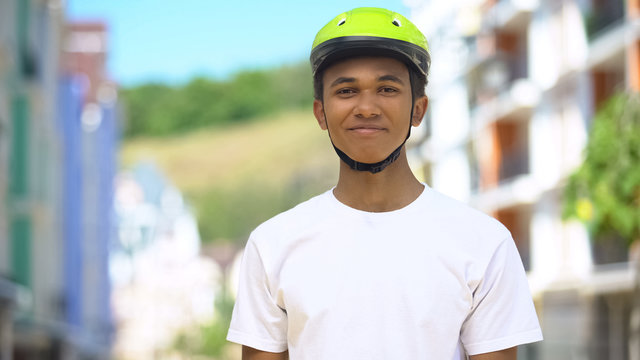 Excited afro-american male teen in protective helmet smiling, cycling hobby