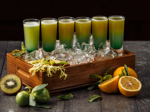wood tray of kiwi and orange shotes served in ice cubes