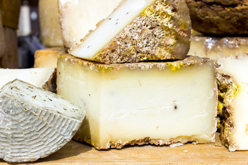 Large selection of cheese varieties on a wooden table background.