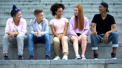 Group of multiethnic young people sitting on academy stairs, leisure time, fun