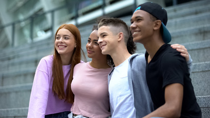 Smiling high-school friends hugging and posing on camera, memory photo, future