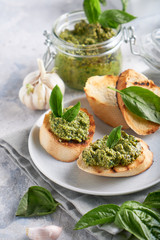 Toasts with traditional Italian basil pesto sauce on a light stone table