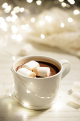 White ceramic cup of hot cocoa with marshmallows on white wooden background.