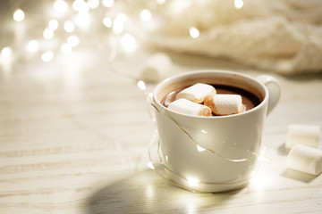 White ceramic cup of hot cocoa with marshmallows on white wooden background