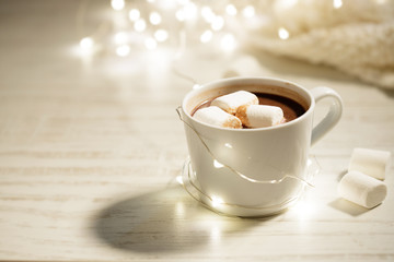 White ceramic cup of hot cocoa with marshmallows on white wooden background
