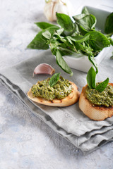Toasts with traditional Italian basil pesto sauce on a light stone table