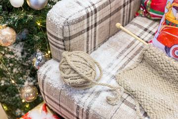 Fototapeta na wymiar A set for knitting lies on a plaid sofa dusted with snow.