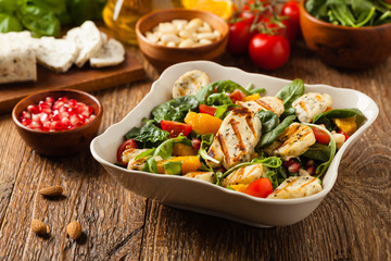 Traditional Greek salad with grilled Halloumi cheese with basil. Front view.