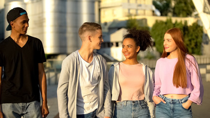 Happy male and female teenagers walking city, international cultural exchange