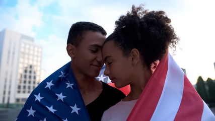 Multiracial teens couple touching foreheads, covered USA flag, tender feelings