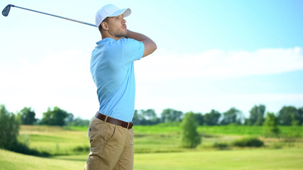 Experienced golf player performing swing hitting ball at course, luxury hobby © motortion