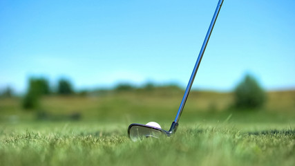 Iron golf club hitting white ball on course, professional sport, elite hobby
