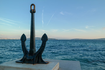 Big steel anchor on the land and the sea in the background. copy space.