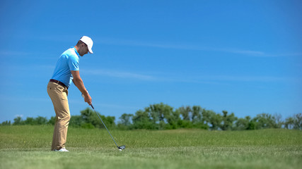 Experienced male golfer hitting ball in swing position, elite hobby and sport