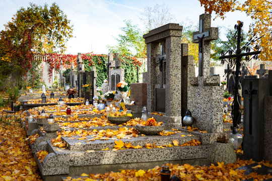 Tombs at a Christian cemetery in the autumn scenery. All Saints Day. Fallen leaves on gravestones.