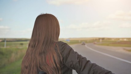 A young girl of 17 years old stands on the road and tries to stop any car.