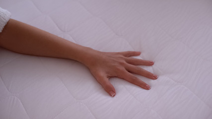 Hand touching mattress, testing elasticity and durability, quality sleep closeup