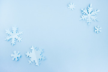 Snowflakes made of paper on a light blue background. Christmas and New Year concept. Background for design, minimal composition. Top view, flat lay, copy space
