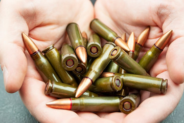 Handful of green 7.62 mm cartridges for Kalashnikov assault rifle in man's hands. Closeup
