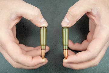 Man's hands are holding two 7.62 mm cartridges for a Kalashnikov assault rifle between fingers