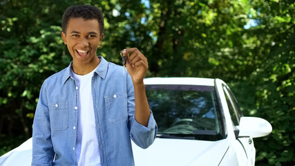 Young black male holding automobile key, transport purchase, driving license