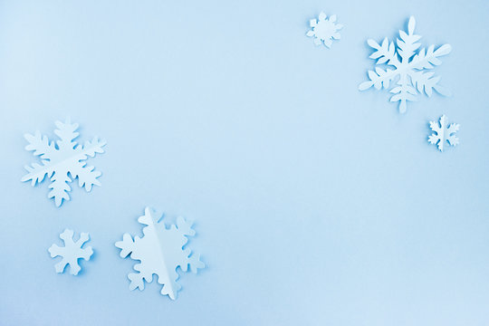 Snowflakes made of paper on a light blue background. Christmas and New Year concept. Background for design, minimal composition. Top view, flat lay, copy space