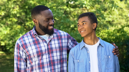 Joyful black son and father smiling each other, trustful relations, friendship