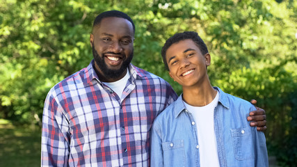 Cheerful black dad and son smiling on camera, trustful relations, friendship