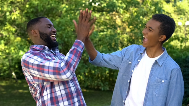 Delighted Black Men Giving High Five, Happy Brothers Enjoying Time Together