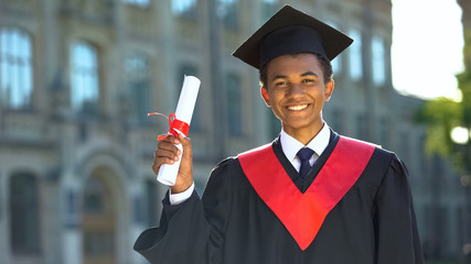 Joyful college student showing diploma celebrating graduation day, achievement