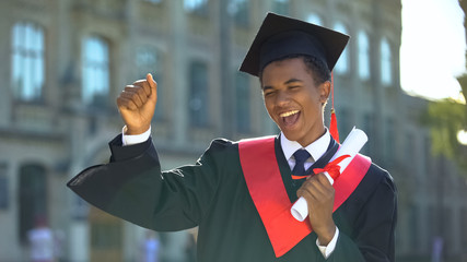 Cheerful male dancing celebrating graduation outdoors university, knowledge