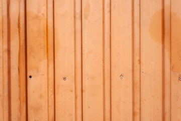 Fototapeta na wymiar Orange metal fence with vertical corrugated stripes