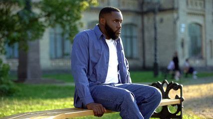 Upset african american male sitting alone on college bench stress after conflict