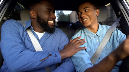 Smiling american father praising son learning to drive auto, parent help, family
