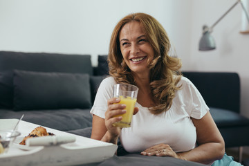 middle aged woman drinking orange juice
