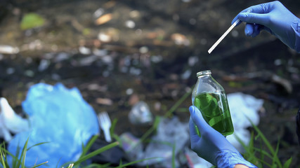 Ecologist with strip measuring heavy metal level in water sample, eco problem