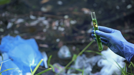 Scientist holding test-tube with radioactive sample from polluted area in forest